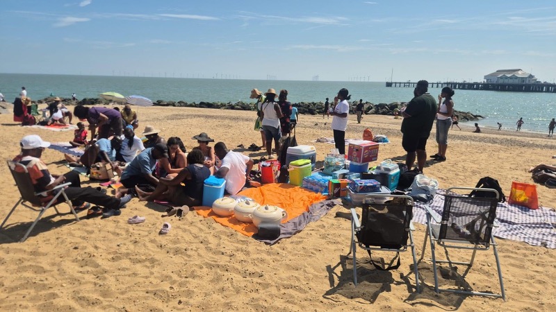 Families gathered on picnic blankets by the sea at the church beach trip