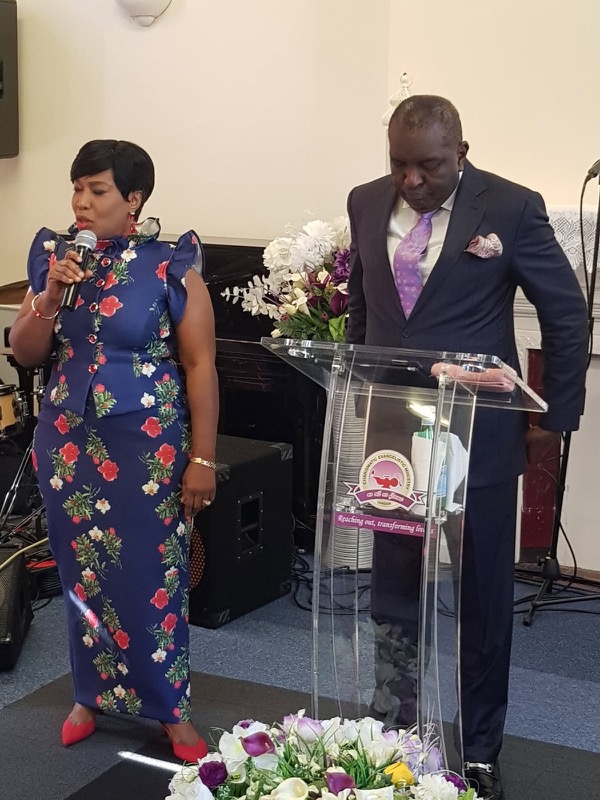 A minister speaking at the pulpit beside a pastor at Divine Encounter