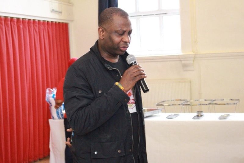 A speaker welcoming guests with a microphone at the Easter Charity Event